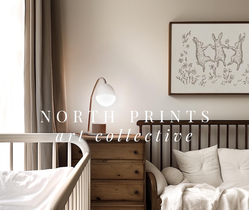 May include: A nursery room with a white crib, a wooden dresser, and a brown couch with white pillows. A framed print of three dancing rabbits hangs on the wall above the couch. The text "NORTH PRINTS art collective" is printed on the wall.