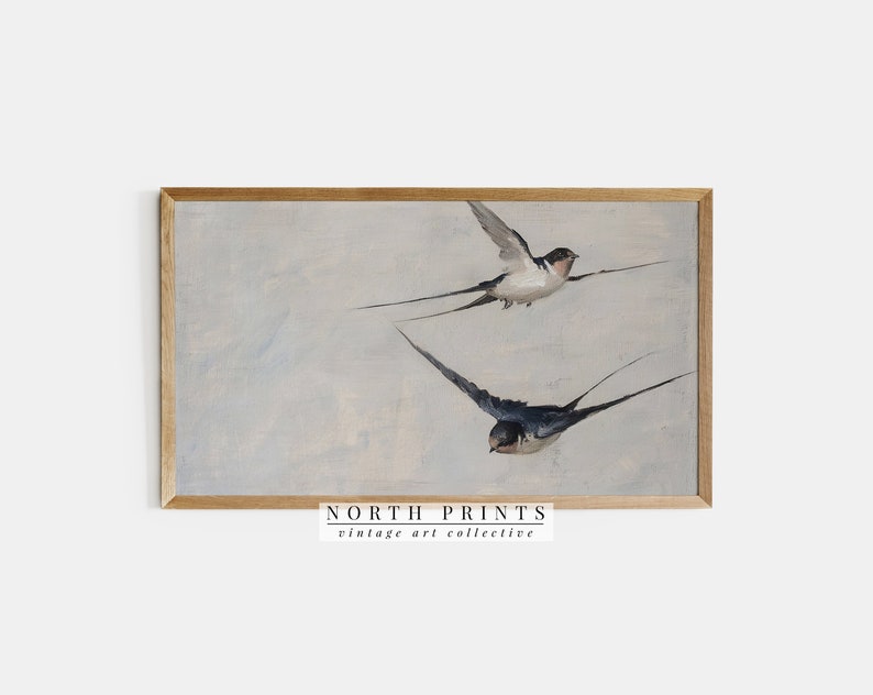 Puede incluir: Una pintura vintage enmarcada de dos golondrinas en vuelo contra un cielo azul claro. La pintura est&aacute; en un marco de madera con un acabado marr&oacute;n claro. El texto "NORTH PRINTS vintage art collective" est&aacute; impreso debajo del marco.