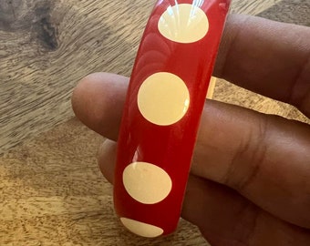 May include: Red bangle bracelet with white polka dots.