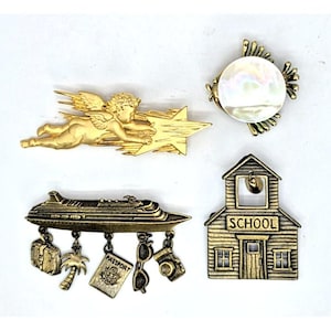 Może przedstawiać: Cztery, stylizowane, metalowe przypinki w odcieniach złota. Jedna przypinka przedstawia cherubina ze skrzydłami i gwiazdą. Inna ma perłowe centrum. Przypinka w kształcie statku wycieczkowego ma wiszące zawieszki o tematyce podróżniczej. Ostatnia przypinka to szkoła z napisem "SCHOOL".