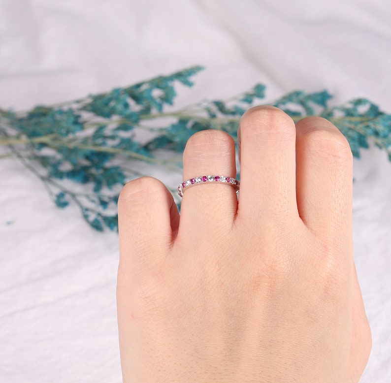 Op de afbeelding: Een delicate eeuwigheidsring met een rij kleine roze edelstenen en witte accenten.