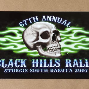 Può includere: Cartello in metallo nero con un teschio e la scritta "67th Annual Black Hills Rally Sturgis South Dakota 2007." Il teschio è centrale, con accenti di fiamma verde su sfondo nero.