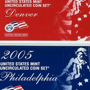 Könnte beinhalten: Zwei 2005 United States Mint Uncirculated Coin Sets. Eines in einer roten Verpackung mit "Denver", das andere in einer blauen Verpackung mit "Philadelphia". Beide zeigen eine Illustration einer Frau und Sterne. Sammlerstücke.