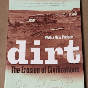 Pode incluir: Capa do livro "Dirt: The Erosion of Civilizations" de David R. Montgomery. A capa apresenta uma imagem em tons sépia de uma paisagem desolada com o título "dirt" em letras brancas grandes. O subtítulo do livro é "The Erosion of Civilizations."