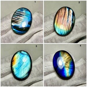 Puede incluir: Cuatro piedras preciosas de labradorita de forma ovalada con variaciones de color iridiscentes. Las piedras muestran una gama de colores, incluyendo azules, verdes, amarillos y naranjas. Cada piedra está pulida y tiene una superficie lisa y reflectante.