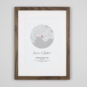 May include: A framed print featuring a circular grey map with a red heart icon marking a specific location. Below the map, the text reads Lauren & Sophia, WHERE WE FIRST MET, TORQUAY, 50 27 44.146 N, 3 31 28.825 W, 12TH JANUARY 2016.