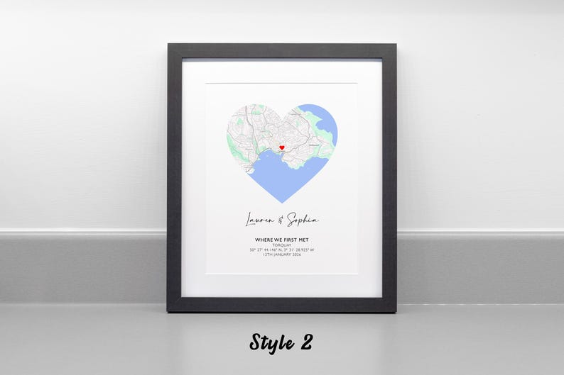 May include: A framed print featuring a heart-shaped map of Torquay with a red heart icon marking a specific location. Below the map, the text reads Lauren & Sophia, WHERE WE FIRST MET, TORQUAY, 50 27' 44.146 N, 3 31' 38.923 W, 12TH JANUARY 2024.