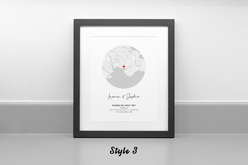 May include: A framed wall art print featuring a circular map of Torquay with a red heart icon marking a specific location. Below the map, the text reads Lauren & Sophia, WHERE WE FIRST MET, TORQUAY, 50 27 44.14N 3 31 38.92W, 12TH JANUARY 2019.