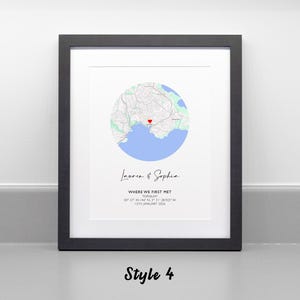 May include: A framed wall art print featuring a circular map of Torquay with a red heart icon. Below the map, the text reads Lauren & Sophia, WHERE WE FIRST MET, TORQUAY, 50 27' 44.148" N, 3 31' 18.923" W, 17TH JANUARY 2016. The frame is black.