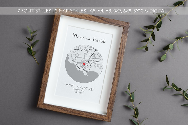 May include: A framed print with a gray and white map of Porthcawl, Wales. The map is centered around a red heart marking a location. The names "Rhian & David" and the text "Where we first met, Porthcawl, Est 201" are printed below the map.