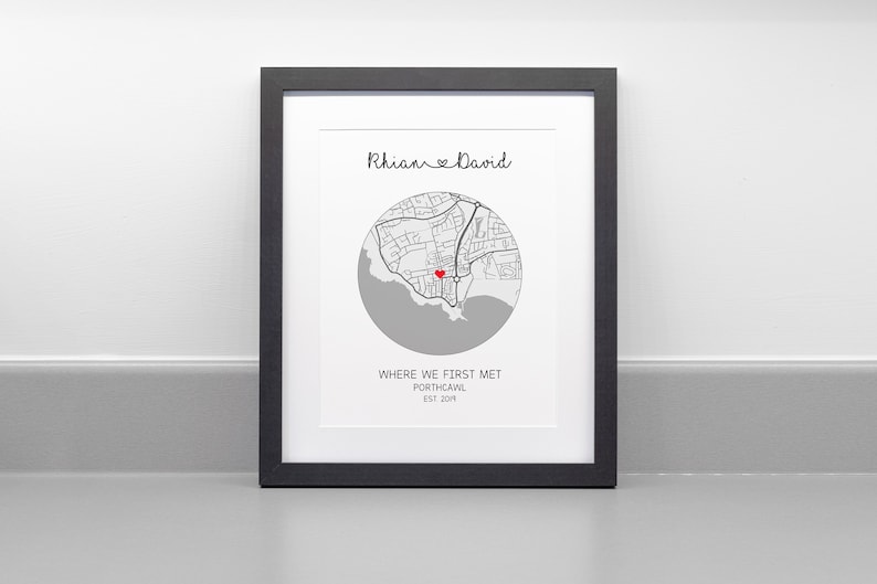 May include: A black framed print with a map of Porthcawl, Wales, with a red heart marking the location where the couple first met. The print reads "Rhian & David" and "Where we first met, Porthcawl, Est 2014."