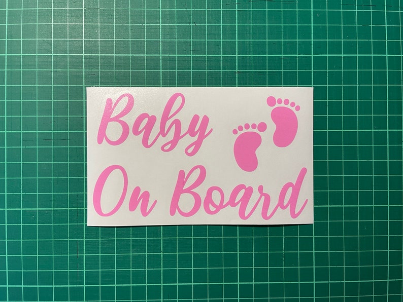 May include: Pink vinyl sticker with the text "Baby On Board" and two pink baby footprints.