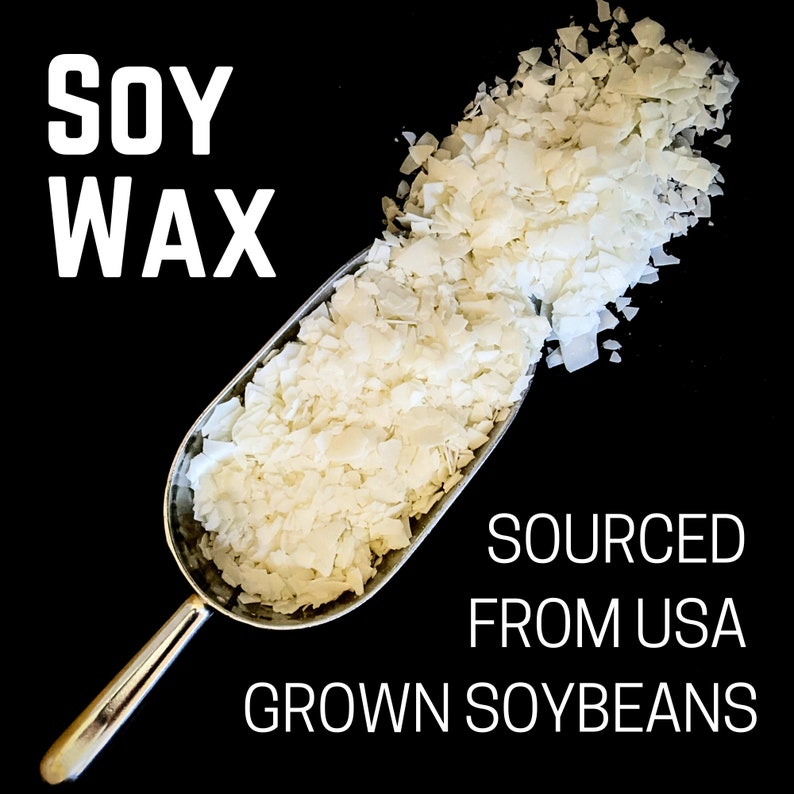 Może przedstawiać: Metalowa szufelka wypełniona białawymi płatkami wosku sojowego na czarnym tle. Słowa "SOY WAX" są dużymi białymi literami. Poniżej tekst: "SOURCED FROM USA GROWN SOYBEANS."