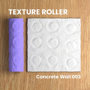May include: A purple texture roller with a pattern of circles. The roller is next to a sample of the texture it creates, a white concrete wall with a pattern of circles. The text "Concrete Wall 003" is below the sample.