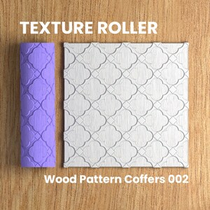 Op de afbeelding: Een paarse textuurroller met een repeterend geometrisch patroon. De roller wordt gebruikt om een decoratief houtpatroon op oppervlakken te creëren. De tekst "Wood Pattern Coffers 002" staat onder de roller.