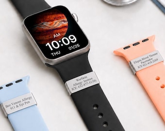 May include: A black smartwatch with a digital display showing 10:09, accompanied by two additional silicone watch bands in light blue and peach. Each band features a silver-toned metal medical alert tag engraved with specific health information.