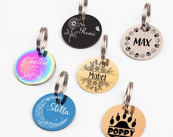 May include: Six different round dog tags with engraved designs and names. The tags are silver, gold, and black with various designs including paw prints, flowers, and a crescent moon.