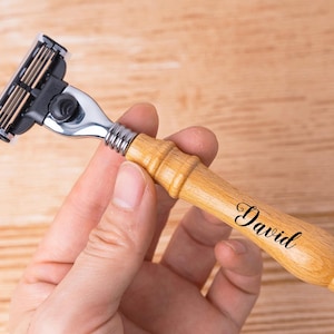 May include: A wooden handled safety razor with a silver head and a black plastic handle. The handle is engraved with the name "David".