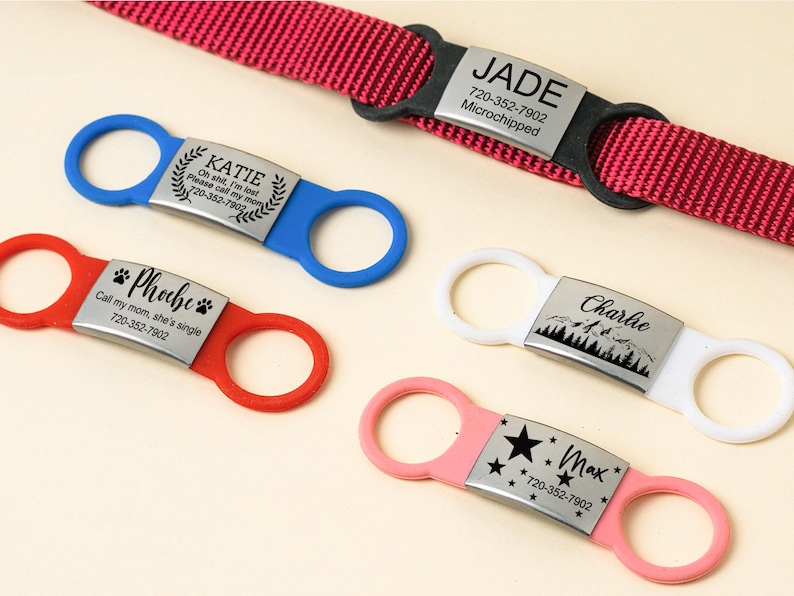 K&ouml;nnte beinhalten: F&uuml;nf verschiedene Hunde-ID-Tags in verschiedenen Farben und Designs. Die Tags zeigen die Namen "Katie", "Phoebe", "Charlie", "Max" und "Jade" sowie Telefonnummern und zus&auml;tzliche Informationen.