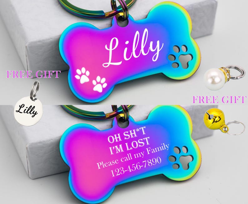Puede incluir: Dos etiquetas para perros en forma de hueso, arco&iacute;ris e iridiscentes, con texto grabado. La etiqueta superior dice "Lilly" con huellas de patas. La etiqueta inferior dice "OH SH*T I'M LOST Please call my Family 123-456-7890".