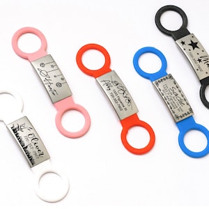 May include: Five colorful pet ID tags with engraved names and phone numbers. The tags are attached to black, pink, white, blue, and orange silicone loops.