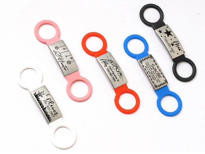 May include: Five colorful pet ID tags with engraved names and phone numbers. The tags are attached to black, pink, white, blue, and orange silicone loops.