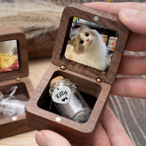 May include: Wooden keepsake boxes with framed photos of a duckling and a cat. One box is open, revealing a small glass vial with a cork stopper and a heart-shaped tag that says "Kitty".