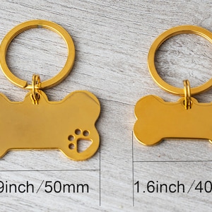 May include: Two gold-colored dog bone-shaped pet ID tags with key rings. The larger tag is 1.9 inches (50mm) long and 1.1 inches (28mm) wide, with a paw print cutout. The smaller tag is 1.6 inches (40mm) long and 0.8 inches (22mm) wide.