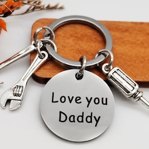 May include: Silver keychain with a round tag that says "Love you Daddy". The keychain has a hammer, wrench, and screwdriver charm.