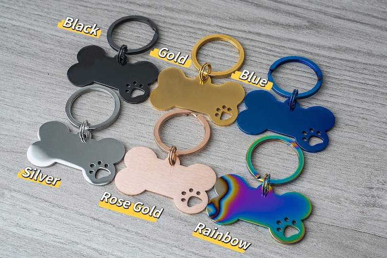 Puede incluir: Seis llaveros con forma de hueso de perro en diferentes colores: negro, dorado, azul, plateado, oro rosa y arco&iacute;ris. Cada llavero tiene un recorte en forma de huella de pata y un anillo de metal.