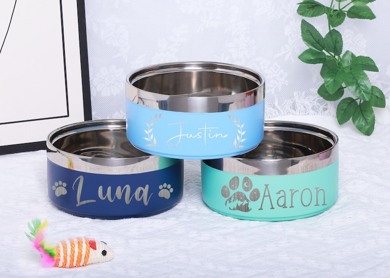 K&ouml;nnte beinhalten: Drei personalisierte Edelstahl-Futternapf f&uuml;r Haustiere. Die N&auml;pfe sind blau, t&uuml;rkis und hellblau. Die Namen sind "Luna", "Aaron" und "Justin".