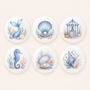 May include: A set of six circular ceramic coasters featuring watercolor illustrations of coastal themes including a mermaid tail, a pearl in a shell, a beach cabana, a seahorse, an open shell with a pearl, and a spiral seashell with seaweed.