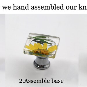 K&ouml;nnte beinhalten: Ein Bild, das die Montage von dekorativen Kn&ouml;pfen zeigt. Der Prozess wird in drei Schritten gezeigt: Komponenten, Basismontage und das fertige Produkt. Die Kn&ouml;pfe haben eine klare, quadratische Harzoberseite mit getrockneten Blumen und eine silberne Basis.