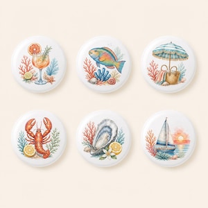 May include: A set of six round white ceramic coasters featuring watercolor illustrations of coastal themes including a cocktail, a colorful fish, a beach umbrella with a basket, a lobster, an oyster with lemon, and a sailboat on the water.