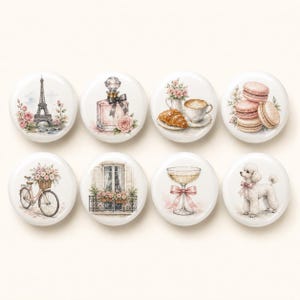 May include: A set of eight round ceramic knobs featuring watercolor-style illustrations of Parisian themes, including the Eiffel Tower, a perfume bottle, a croissant with coffee, macarons, a bicycle with flowers, a balcony, a glass, and a poodle.