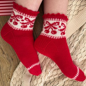 Peut inclure: Une paire de chaussettes tricotées à la cheville, rouge vif, avec un revers blanc orné d'un motif répétitif de nœuds rouges. Les chaussettes présentent un bord supérieur volanté et un détail de rayure horizontale blanche près des orteils.
