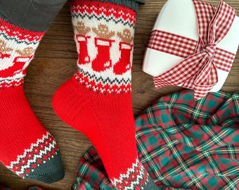 May include: A pair of red and white Christmas socks with a gingerbread man design. The socks are worn by a person sitting on a wooden floor. A white gift box with a red and white gingham ribbon is in the background.