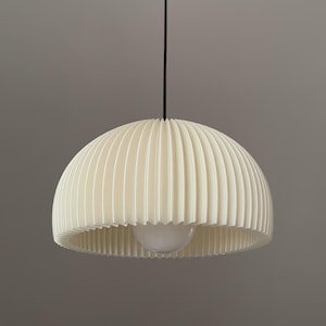 May include: A dome-shaped pendant light fixture featuring a pleated off-white shade with vertical ridges. The lamp hangs from a thin black cord attached to a small black circular ceiling canopy, with a single white bulb visible inside the shade.