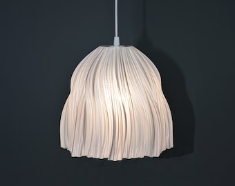 May include: A white pendant light with a unique, pleated, wavy, fabric shade. The light is hanging from a white cord against a dark gray background.