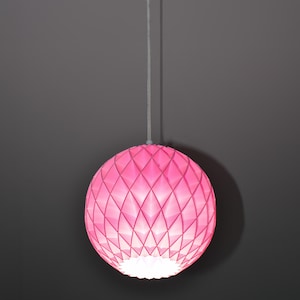 May include: A pink, geometric, paper lantern pendant light hanging from a white cord against a gray background.