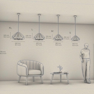 May include: Four sizes of a white, origami-style pendant light fixture hanging from the ceiling. The pendant lights are labeled XL, L, M, and S. Measurements in inches and millimeters are provided for each size. A person stands next to the smallest size pendant light. A chair and a small table are in the foreground.