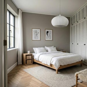 A bedroom featuring a wooden bed frame with white bedding, two wooden nightstands, and a white pendant light. The walls are painted a neutral gray, decorated with two framed line art prints, and the floor has a herringbone wood pattern.