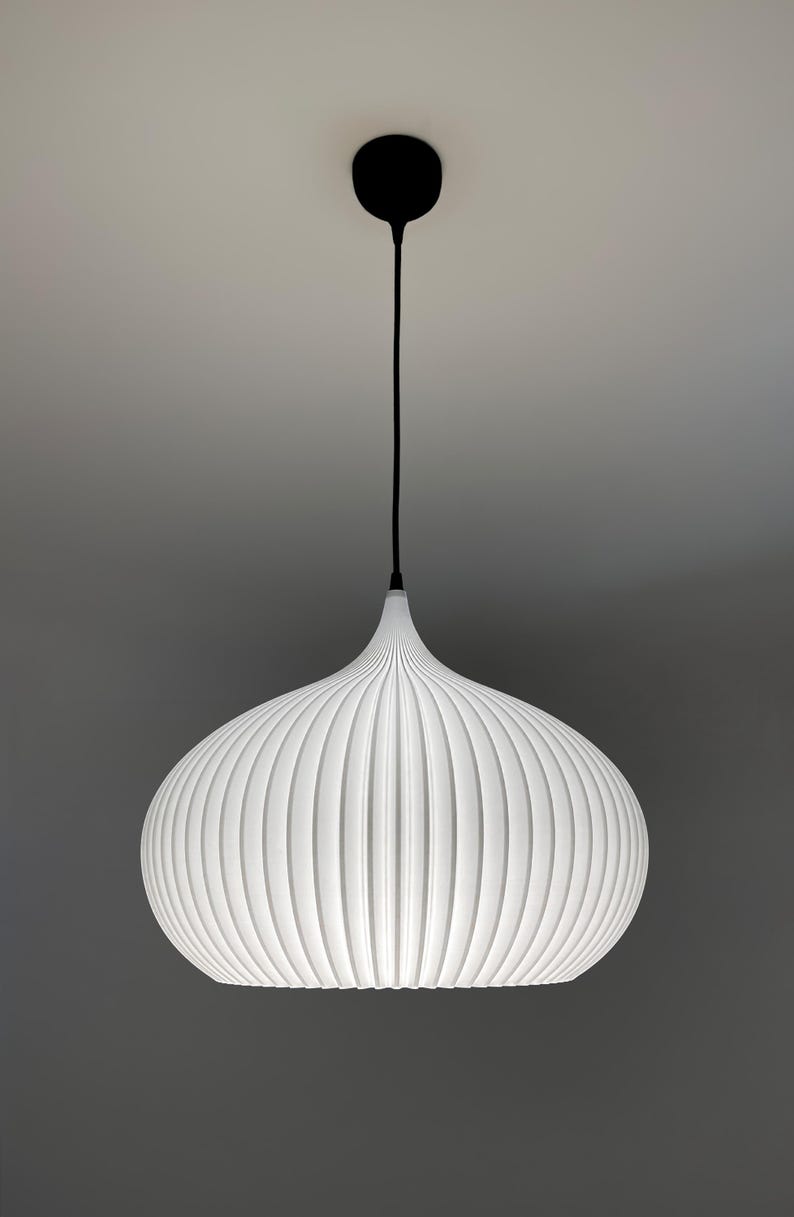A white pendant light with a rounded, ribbed, onion-shaped shade. The fixture is suspended by a thin black cord attached to a small, circular black ceiling canopy. The shade features vertical ridges that create a textured appearance.