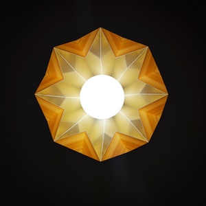 May include: A star-shaped light fixture with a wooden frame and a white light bulb in the center. The light fixture is illuminated, casting a warm glow.