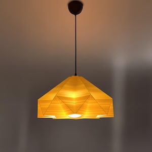 May include: A modern, geometric pendant light fixture with a yellow wood-like shade. The shade is made up of multiple triangular panels, creating a unique and stylish design.