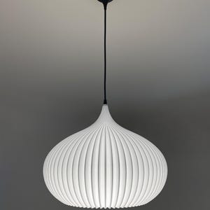 A white pendant light with a rounded, ribbed, and pleated shade. The fixture is suspended by a thin black cord attached to a matching black circular ceiling canopy, creating a clean, symmetrical, and focused lighting element.