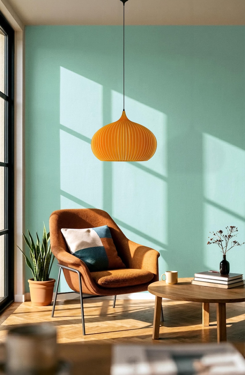 Peut inclure: Une suspension orange vif avec une forme arrondie et nervur&eacute;e, suspendue par un fin cordon noir. Le luminaire pr&eacute;sente une s&eacute;rie de lattes verticales cr&eacute;ant une silhouette sym&eacute;trique distincte, diffusant la lumi&egrave;re vers le bas de mani&egrave;re uniforme.