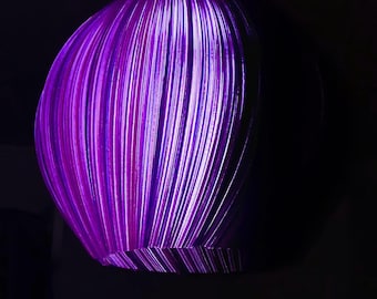 May include: A spherical pendant light fixture featuring a ribbed, textured surface that glows with a vibrant purple light. The structure consists of vertical, curved panels that create a layered, dimensional effect against a dark background.