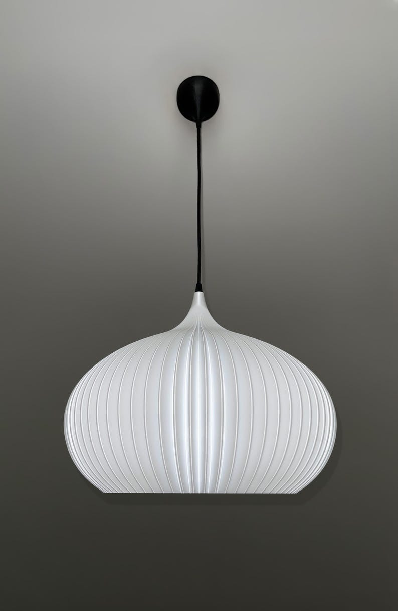 A white pendant light with a rounded, ribbed, and bulbous shade. The fixture is suspended by a thin black cord attached to a small, circular black ceiling canopy. The shade features vertical ridges that create a textured appearance.