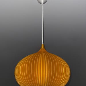 Peut inclure: Une suspension lumineuse jaune dor&eacute; avec une forme arrondie, c&ocirc;tel&eacute;e et semblable &agrave; une citrouille. La lampe pr&eacute;sente une partie sup&eacute;rieure lisse et effil&eacute;e qui se connecte &agrave; un cordon blanc et &agrave; un support de plafond circulaire assorti.
